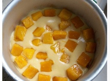 step6: 從雪柜中取出已雪好的餅底，大約將芒果蓉分成三份,先加入一層芒果蓉，再舖一層芒果粒。 再重覆舖一層芒果蓉及芒果粒，中間位置留空,再由冰格取出已雪硬的50gm芒果蓉舖上去中間位置,再加上一層芒果蓉蓋好