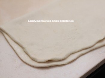 step2: 4.在工作枱上灑上少許手粉，取出麵糰，擀薄成半厘米厚。
5.平均抹上薄薄一層油，對摺。