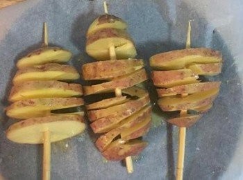 step2: 將馬玲薯用叉子叉起來，從最尾端開始延著竹籤斜切，切後再慢慢的拉轉開，均勻塗滿奶油和橄欖油，