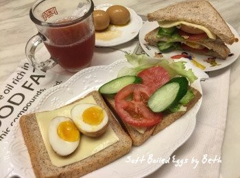 step6: 取2片吐司，一片放上起司片、對半切的溏心蛋；一片放上生菜、蕃茄片、黃瓜片，將2片吐司餡料部分朝內蓋上，再斜切成2個三角形疊起，就是一份三明治了