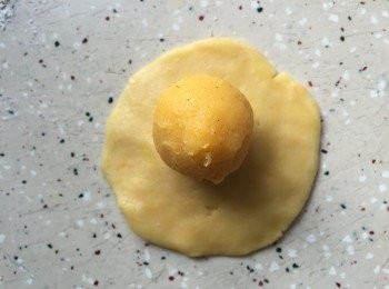 step11: 11. 先取月餅皮,將它以面棍碌開成圓形,中間較厚,圍邊較薄,放入一粒奶皇饀,然後包好成圓形,略收成圓柱體,將月餅模掃上少許低筋面粉,面團放入月餅模中印出花紋,放在舖有牛油紙的焗盆上,重覆以上步驟,然後將月餅放入雪柜中雪至少一小時