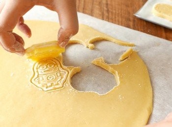 step9: 撕走麵團上的一張牛油紙後，在麵團上以曲奇模印出曲奇。印出曲奇後剩下的麵團可以再捏成一團，重覆桿、冷藏和印模的步驟做出更多曲奇。