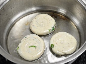 step17: 起油鍋，下蔥油餅，用小火煎，煎邊可以邊壓，這樣蔥油餅會比較快煎熟。