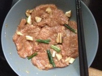 step3: 把肉片置於盤內，加入生粉（10g）、花生油、醬油、少量胡椒粉（沒有可以不用），再加入拍扁的蔥頭和蒜頭，攪拌均勻後，醃製4小時，期間翻面一次。