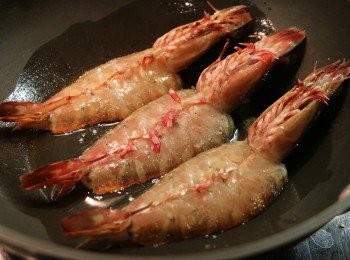 step3: 熱油鍋，先將蝦肉的腹部放下大火煎，再用鍋鏟按壓一下，便於定型。