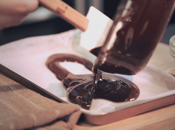 step3: 將薄底不透綱盆上鋪一層牛油紙並倒入已溶好的黑朱古力漿，將其平均掃均至每個角落，待室溫放涼凝固為止