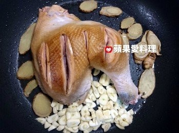 step8: 雞皮煎到金黃色時，翻面續煎；在鍋內的空地，放入蒜頭，利用鍋底的麻油和雞油爆香。