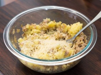 step6: 薯仔蒸的時候用保鮮紙包好，所以蒸好後碟內應該不會太多水份，如有請倒掉多餘水份。薯仔趁熱用壓薯器或大叉子壓成薯蓉，加入炒好的洋蔥肉碎，刨上巴馬臣芝士後拌勻，試味調整味道，然後放涼至用手可處理的溫度