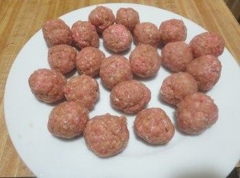 step3: 握住适量的肉馅，从大姆指和食指中挤出肉圆子。油锅烧热后，转中小火，放入肉丸子慢炸至表面金黄，即可