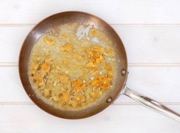 step2: 炒鍋裡放1大匙油,中火加熱,放入鹹蛋黃碎用鍋鏟邊壓邊炒,慢慢地就會融化變成金沙,炒到蛋黃沙冒出泡泡,蛋黃才不會有腥味,再加入蒜末拌炒出香氣。