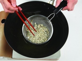 step6: 將鯷魚乾放入網篩，放到先前炸過豆腐的油鍋裡酥炸。(也可用蝦米代替鯷魚乾。)
