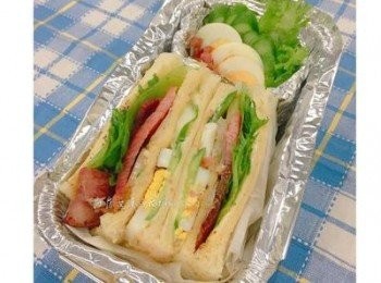 step8: 取鋁箔盒將對切的三明治放入後，另外用鋁箔紙做ㄧ個小盒，放入剩下的蛋片、生菜和洋蔥片，及切小塊的培根，並撒上少許黑胡椒粉即可。