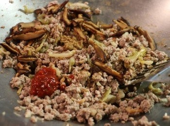 step4: 當肉碎炒至變白後，放入榨菜和香菇片翻炒均勻。