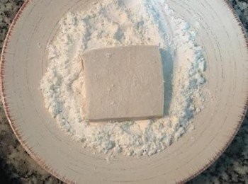step5: 不沾鍋燒熱後放入適量的油，
將切片的豆腐兩面沾上薄薄的玉米粉。