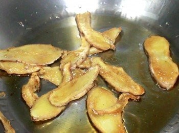 step3: 以小火, 最小的火, 用黑芝麻油把老薑片煸至乾身, 至棕色出現。
麻油不耐高溫，如果用麻油爆香，千萬不能出煙。所以，用麻油爆香時要用小火，慢慢煸出香氣。如果對火侯控制沒有自信者，可用食用油爆香薑片，在煮雞飯時，再加入麻油。