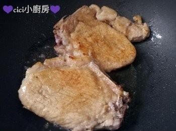 step3: 將豬扒兩面撲上生粉, 燒熱煎鑊, 放下豬扒, 用中火先煎兩面略微金黃色，再轉慢火煎熟。 盛起, 用廚房紙吸乾油份, 切成條, 備用。