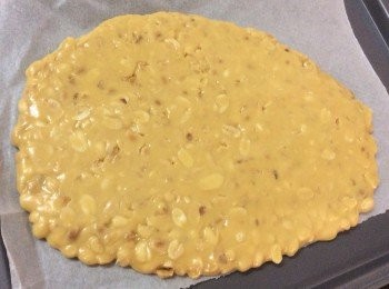 step5: 将搅拌好的牛轧糖团倒进已铺上油纸的烤盘上。
在牛轧糖团上再铺上另一张油纸，用擀面棍擀平