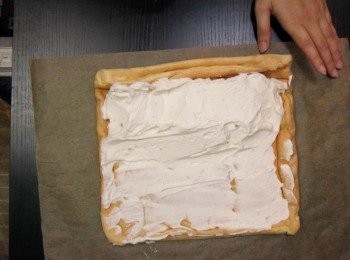 step15: 把已定型的蛋糕卷攤開
向自己的一邊把所有忌廉（淡奶油）倒下抹開，9成忌廉（淡奶油）在起始處，收尾只抹少許即可