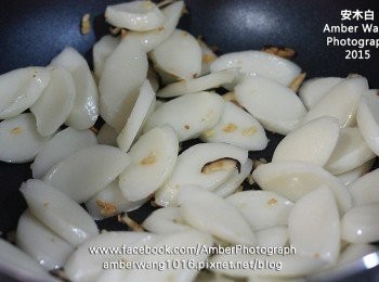 step2: 熱鍋後倒入一匙油，放入蒜末爆香，再放入香菇炒香，接著放入年糕片，略為拌炒。然後倒入半碗水，蓋上鍋蓋一會，讓年糕片蒸熟。