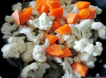 step3: 加入菜花和萝卜并倒入一杯水的分量。然后盖上锅盖，煮至菜花和胡萝卜变软。