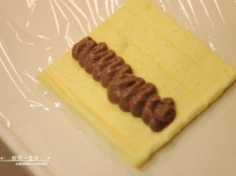 step16: 取一塊小蛋糕放在保鮮膜上，中間擠上適量<span class="group_1">巧克力香蕉卡士達餡</span>。