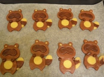 step12: 最後取適量深啡色麵糰，揉成小圓粒，蘸一點蛋液放在浣熊的頸部兩邊，形成小圓手；原色麵糰揉成小圓粒放在耳朵上。