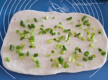 step2: 搓好之麵糰用麵糰棒桿平， 面層薄薄的掃上一層樓油跟手灑上蔥花、 將上層覆往下層