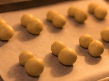 step9: 每一塊用手搓成球形，然後一個大球併著一個小球置於已鋪牛油紙之焗盤上（請勿過度搓壓粉麵團，因牛油會溶化，只要大約造型就好）
整盤放入雪櫃中約15分鐘，其間預熱焗爐至170度