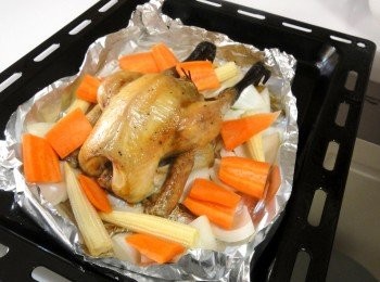 step5: 將烤箱預熱至230度，在烤盤塗上少許奶油，入烤箱烤30分鐘，取出烤雞，在鍋子底部放入洋蔥、玉米筍、紅蘿蔔再入烤箱烤10分。