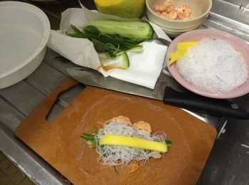 step3: 開一盆凍滾水 (可放入米紙)，將一片米紙放入水中待20秒至軟身，雙手取起沾水的米紙平放在木板上將材料置中，(如上圖)，上方放蝦，青瓜絲、甘荀絲、粉絲、九層塔及芒果，將上邊米紙向中間翻下，兩方對摺再卷起