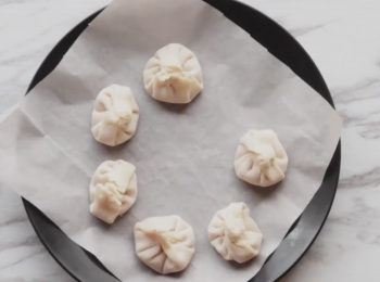 step7: 烘培紙舖在碟上,小籠包放上
Put a sheet of parchment paper on a heat proof plate and place inside frying pan.