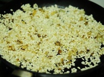 step2: 下少許油，先下蒜蓉及洋蔥，炒約兩分鐘至軟身。然後下米，炒一分鐘