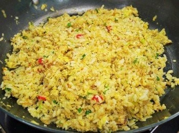 step2: 步驟2：
將蒜末、辣椒末1/2、魚露、冷開水、糖並擠入檸檬汁拌勻成醬汁備用，取鍋熱油放入蔥白末、洋蔥末、辣椒末1/2、蟹腿、米酒炒香，接著倒入蔥綠末、蛋汁、醬油、白飯炒勻至飯粒油亮且粒粒分明，調入鹽、白胡椒粉後即完成。