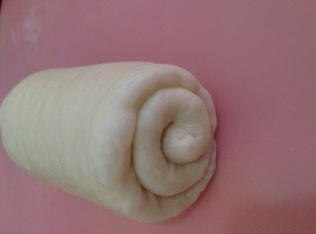 step8: 7..  從上端向下輕拉卷起麵團（約卷兩圈半），用手指捏緊收口，收口朝下，排入模具中。