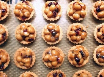 step20: 趁熱用湯匙將夏威夷豆放入烤好的<span class="group_2">塔皮</span>裡,最後再將完成的豆塔送進烤箱以180度c烤5分鐘即可出爐。