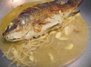 step4: *將煎好的魚輕推到一旁，再下一匙沙拉油爆香薑絲，蒜片。至香氣出。
*倒入水，米酒煨煮。至魚湯味香氣出~