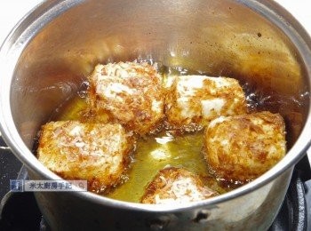 step3: 小煲燒熱1-2碗油。豆腐順序沾上麵粉、蛋液、柴魚片，放入煲中以中火炸至金黃後，放在鐵架上滴乾油分。