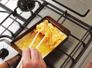 step5: 使煎蛋滑向煎鍋前半部，於空出的後半部塗油，約倒入剩餘蛋汁的1/3，並用長筷抬起前半部的煎蛋，使蛋汁流入下方。