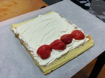 step10: 將蛋糕放在另一將牛油紙上，均勻地塗上忌廉，放上水果, 將蛋再度卷起成瑞士卷狀