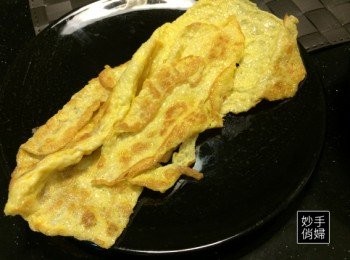 step2: 雞蛋打散之後加入鹽巴一小匙,平底鍋加熱加油之後放入打散的雞蛋煎至兩面呈現金黃色,用刀子或剪刀把煎好的雞蛋切成小條狀,