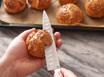 step13: 將製作好的卡士達醬，在耐熱鐵盤上鋪開，再不留縫隙的覆上保鮮膜。在鐵盤下墊著冰水，加速冷卻。 將鮮奶油打至6分發（將鮮奶油打發至表面黏稠痕跡會立即消失的狀態。）後，加入卡士達醬中攪拌，再填入已經裝上星形擠花嘴的擠花袋中。 切開11上部的⅓，將鮮奶油卡士達醬擠進下半部的泡芙中，再將上半部蓋回。