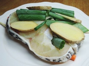 step3: 龍膽石斑要料理前一晚，先放在冷藏退冰，將盤底先擺上兩根筷子，在放上龍膽石斑，然後淋上一大匙米酒，擺上薑片與蔥段，進電鍋，外鍋一杯水蒸熟