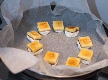 step5: 平底鍋中鋪一張牛油紙，圍圈放上多士（棉花糖向下），以慢火加熱約 20 – 30 秒至棉花糖表面呈金黃色即成。