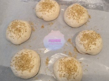 step4: 每份麵糰用手/麵粉棍擀成麵皮包住4-6粒芝士，滾圓，放喺焗爐紙上。(麵皮要中間比周邊薄，大約手掌咁上下大) 6個麵糰包好晒之後，喺表面噴/掃少少油/水，灑上芝麻粒。用保鮮紙略為蓋住，放喺溫暖地方再進行第二次發酵，約15-30分鐘。