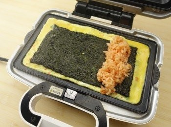 step3: 若1分鐘蛋漿開始凝固，將紫菜覆蓋在上。再在紫菜上平均放置一行用韓式辣醬調味的飯，從一端開始用筷箸慢慢捲起蛋皮。