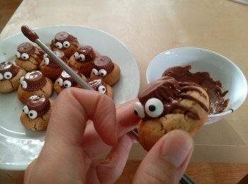 step7: 当饼干烤好待凉2-3分钟放上蜘蛛身。饼干不能太热放因为会溶化蜘蛛身，但太冷会粘不住。等饼完全冷后，才用巧克力醤画上蜘蛛脚。