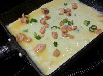 step8: 用一個專整蛋卷的鑊,搽少許油,用湯殼筆一穀蛋漿,加少許三文魚蔥粒平均舖上,用最慢火將蛋卷煎熟(蛋漿不要落太厚,否則會難卷)(不要煎太耐,見蛋漿開始凝固即可)