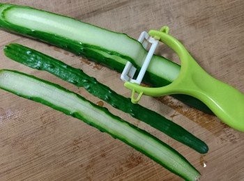 step1: 將小黃瓜放在帖板上，一手壓著小黃瓜，另一手用削皮刀將小黃瓜刨成片狀。