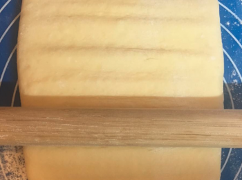 step8: 枱面同木棒都要掃麵粉，將粉團收口位向下，由上至下將粉團壓開。牛油少少淋時將粉團碌至18cm長。（動作要快，唔好俾舊牛油溶哂落粉團。）