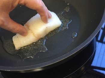 step8: 煎魚用易潔鑊，先開大火加橄欖油。放入鱈魚，皮向下，用手指輕輕把魚塊按壓在鑊面。使魚皮可以全面接觸到鑊面。煎起來會更加均勻。轉中慢火，慢慢煎烤魚皮。大約八至十分鐘。期間不要轉動條魚。最接近鑊面的魚肉熟了會向上慢慢變淺色。直到魚肉大約三份二左右熟時。可以返轉魚身，然後熄火。利用鑊的餘溫煎熟底部。